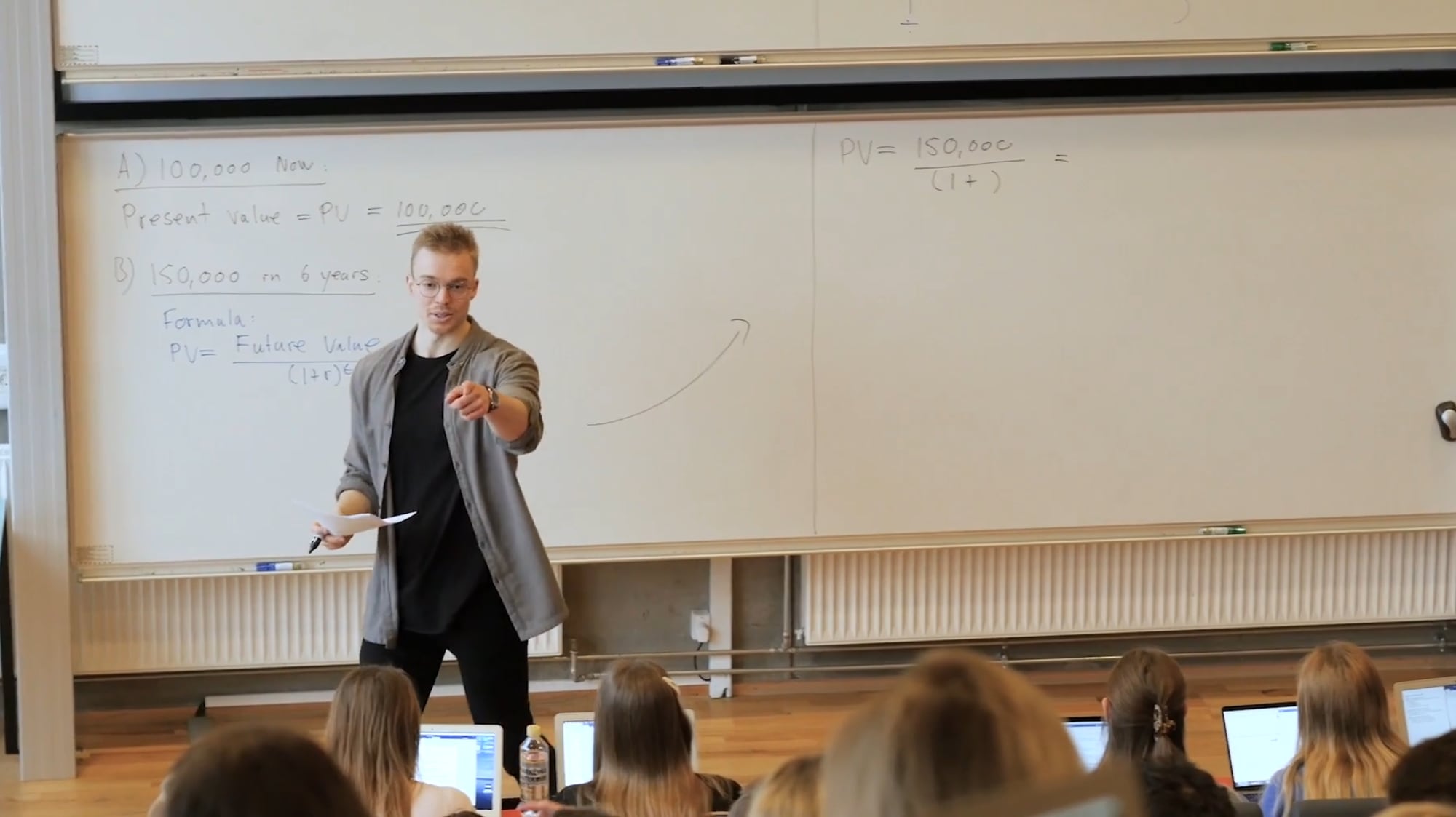 Kim teaching a finance lecture, pointing at a student