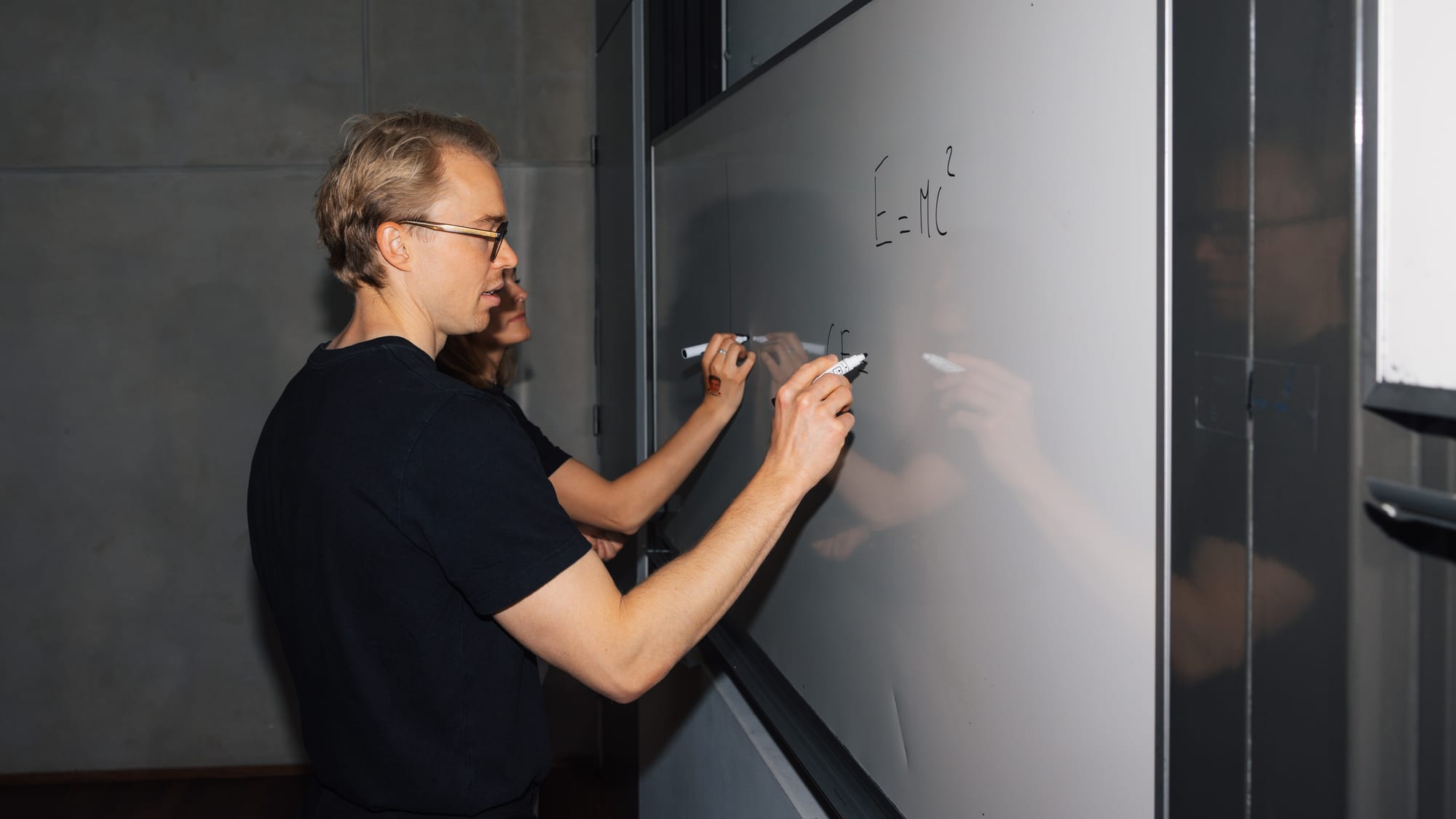 Kim Rants at a whiteboard, writing next to a student